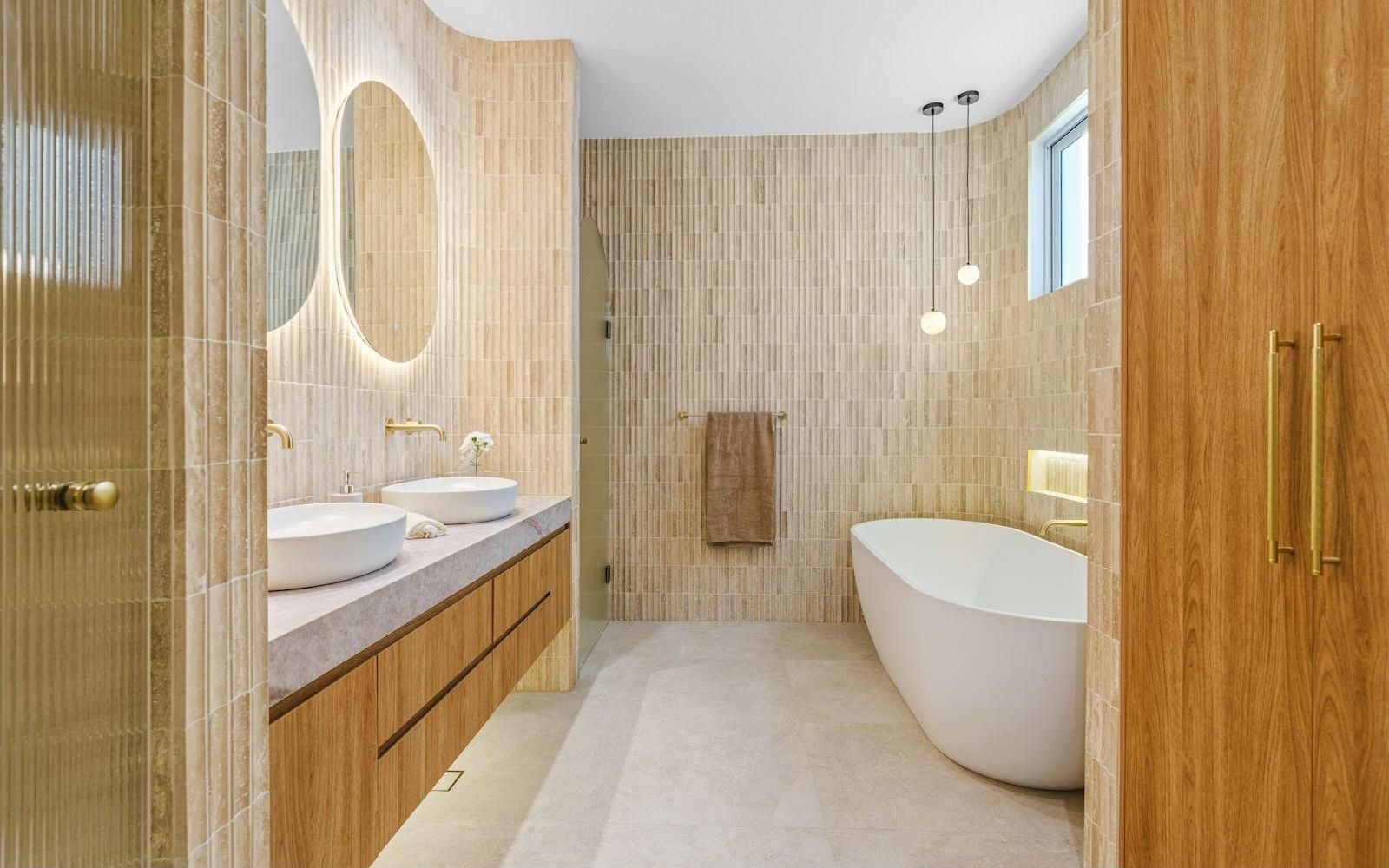 Renovated bathroom with tiled walls, freestanding tub and brass fixtures